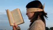 Kvinde med bind for øjnene holder bog op som for at læse